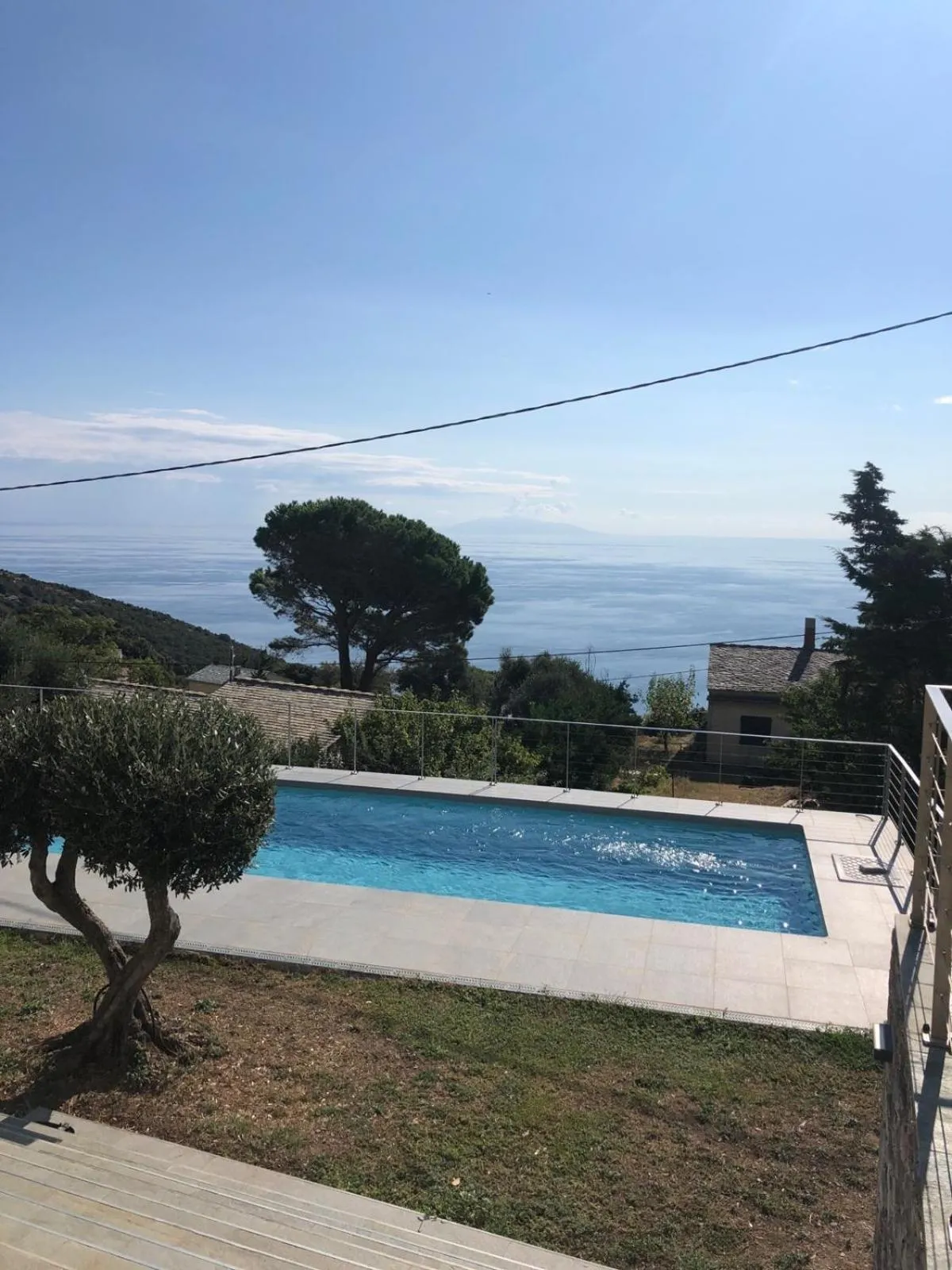 Une piscine rectangulaire avec une vue sur la mer et la végétation environnante.