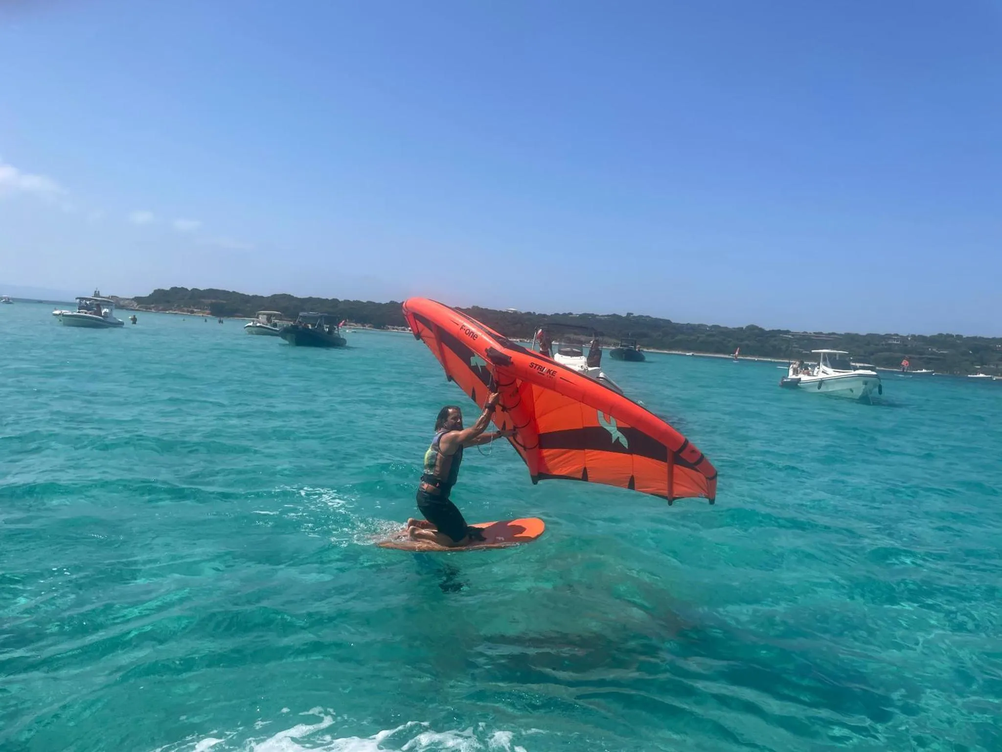 Une personne pratique le wingsurf sur une eau turquoise.
