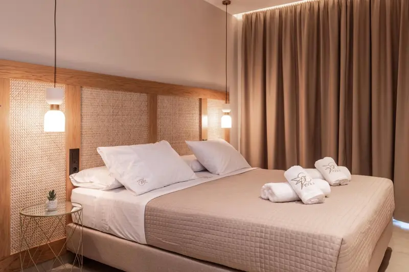 Une chambre lumineuse avec un grand lit recouvert de draps blancs et de coussins.