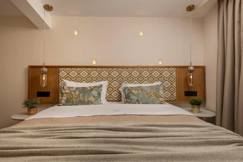 Une chambre lumineuse avec un grand lit recouvert d'une couverture et de coussins.