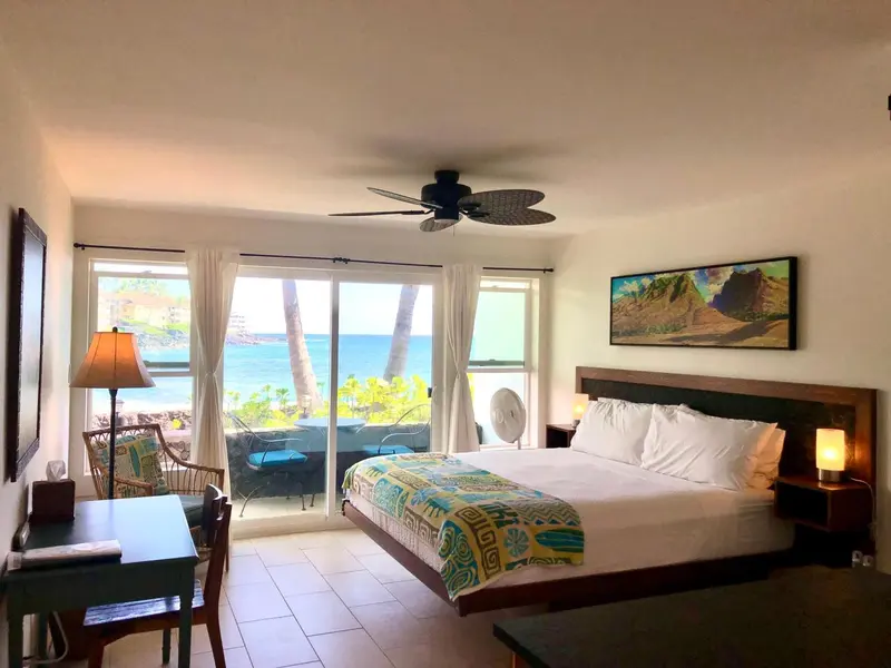 Une chambre lumineuse avec un grand lit face à une baie vitrée donnant sur la mer.