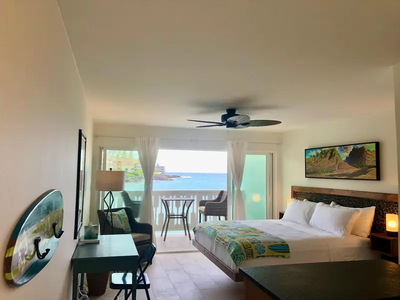 Une chambre lumineuse avec un lit et un bureau donnant sur la mer.