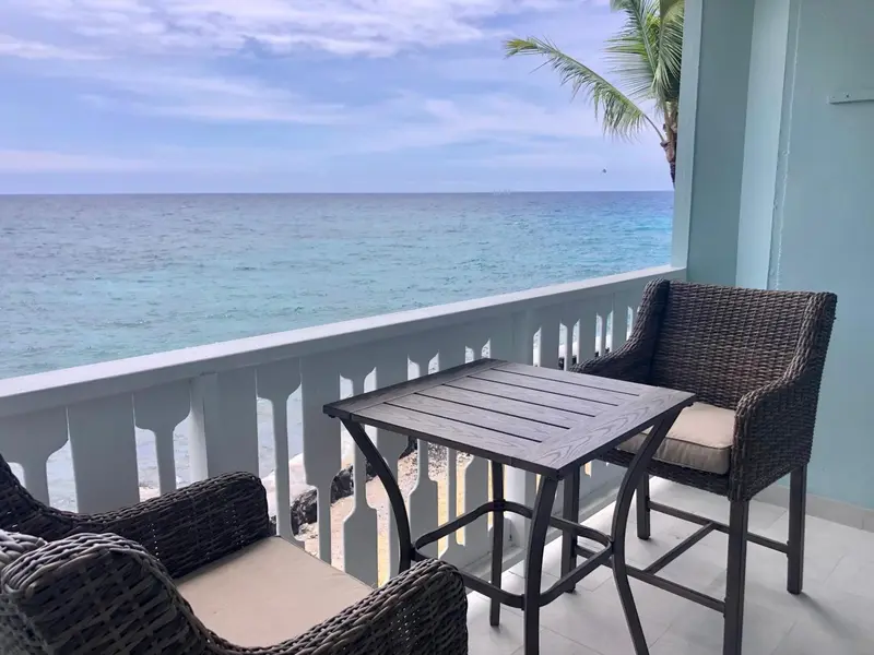 Terrasse avec mobilier en osier donnant sur la mer turquoise.
