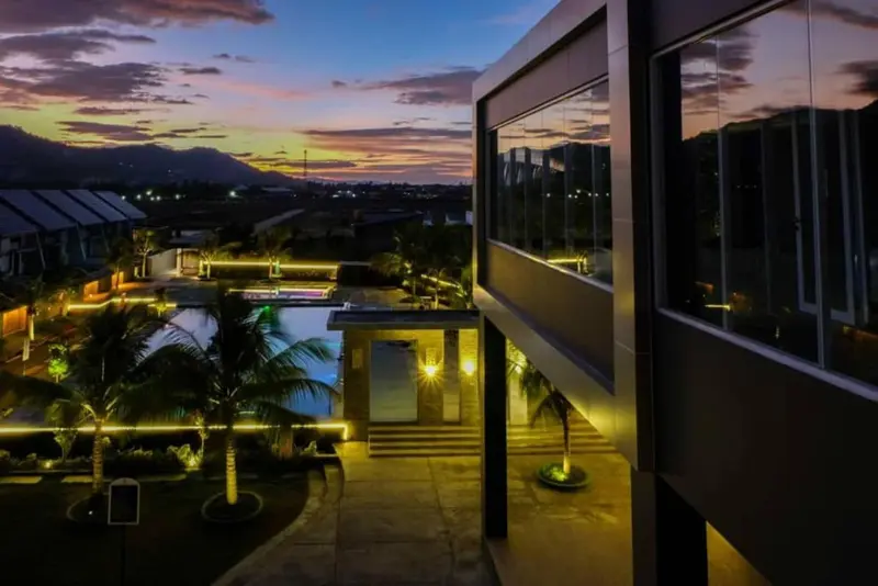 Vue d'un bâtiment moderne avec une piscine illuminée au crépuscule.