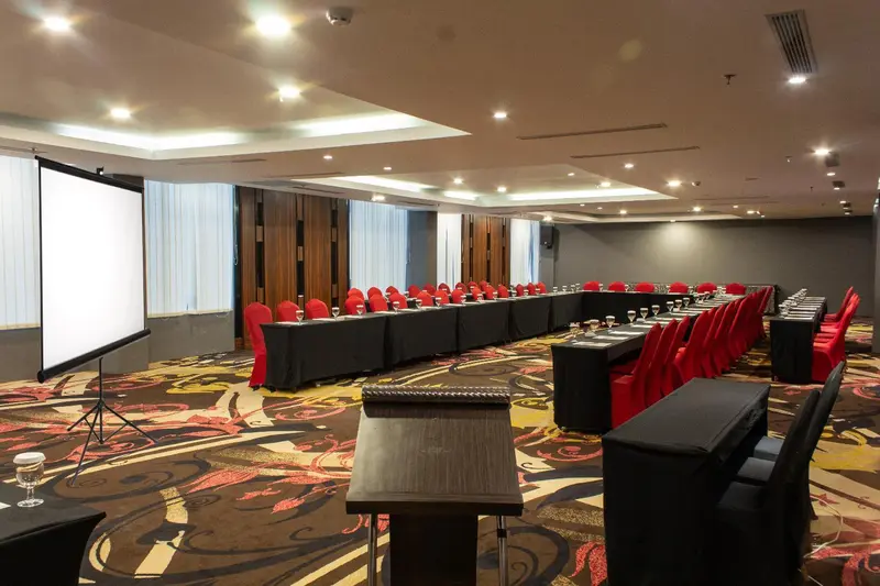 Une salle de réunion spacieuse avec une longue table et des chaises rouges.