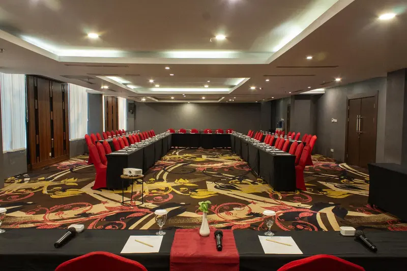 Une longue table de réunion est disposée en U dans une salle spacieuse.