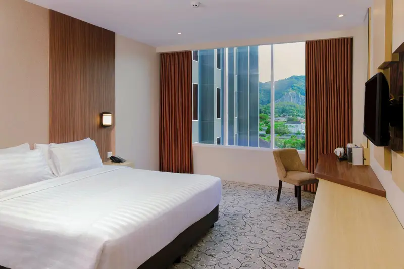 Chambre lumineuse avec un grand lit et une vue sur le paysage.