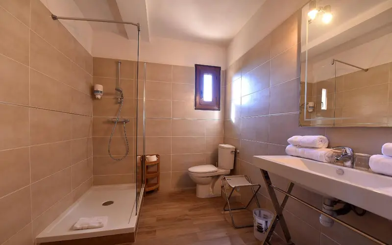 Une salle de bain claire avec douche à l'italienne et lavabo.