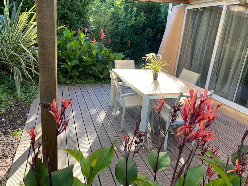 Une table à manger blanche est entourée de chaises sur une terrasse en bois.
