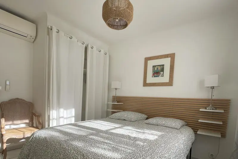 Une chambre lumineuse avec un lit double et un fauteuil.