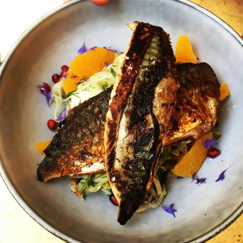Assiette de poisson grillé accompagné de légumes et d'agrumes.