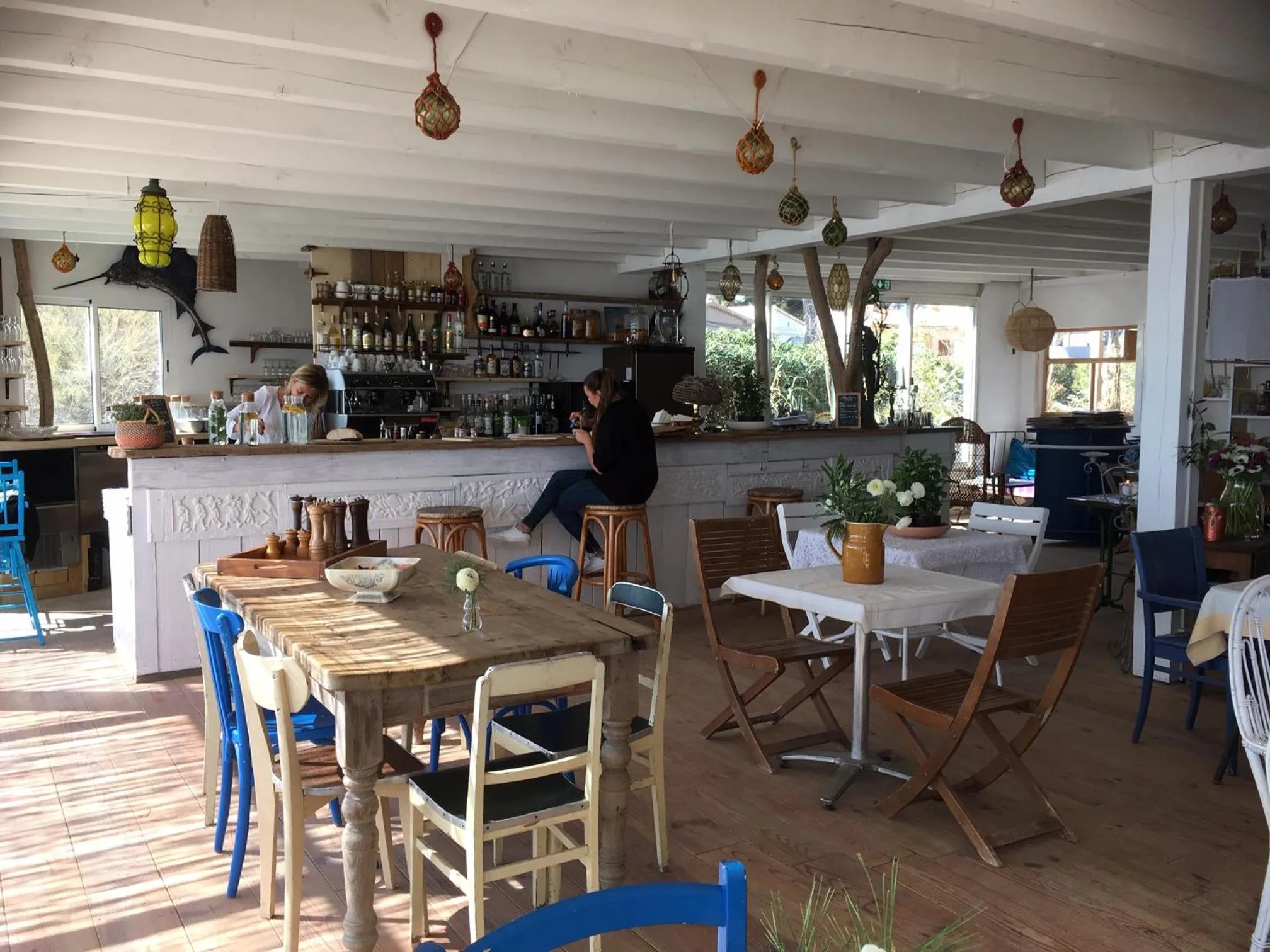 Un bar en bord de mer propose des boissons et des repas sur une terrasse en bois.