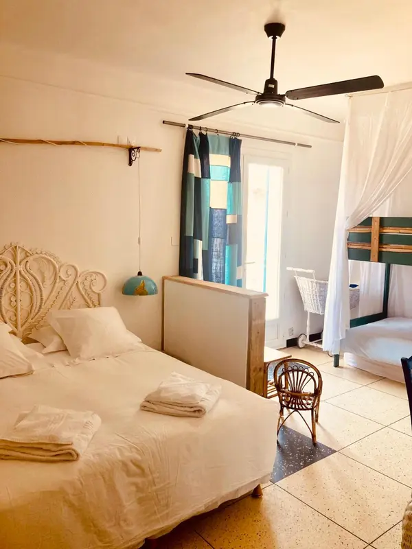 Une chambre lumineuse avec un lit recouvert de linge blanc et une moustiquaire.