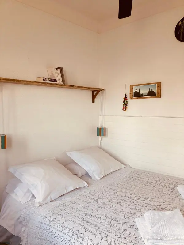 Une chambre lumineuse avec un lit recouvert d'une courtepointe blanche et de coussins.