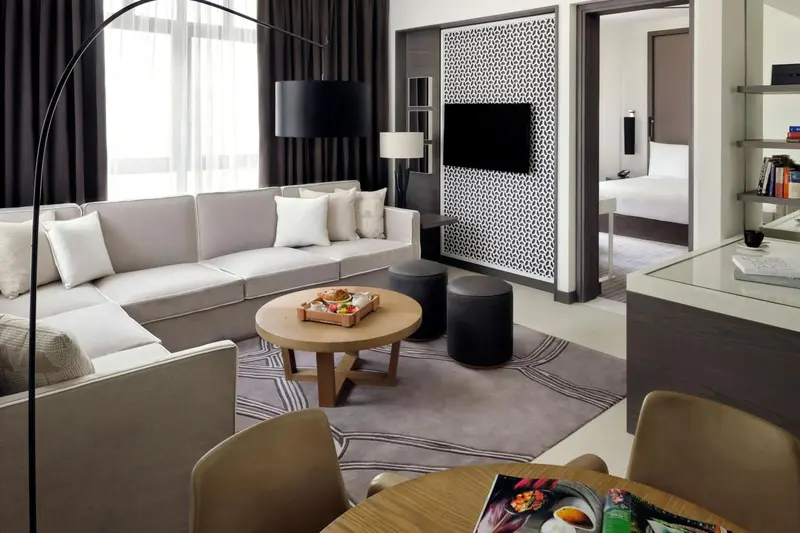 Un salon moderne avec canapé gris, table basse et télévision murale.