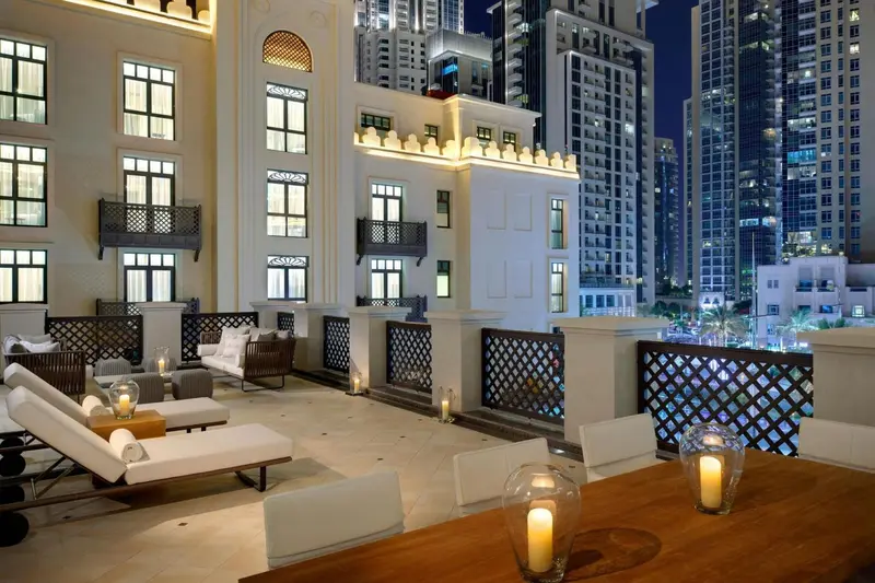 Terrasse aménagée avec salon et table à manger donnant sur une vue urbaine nocturne.