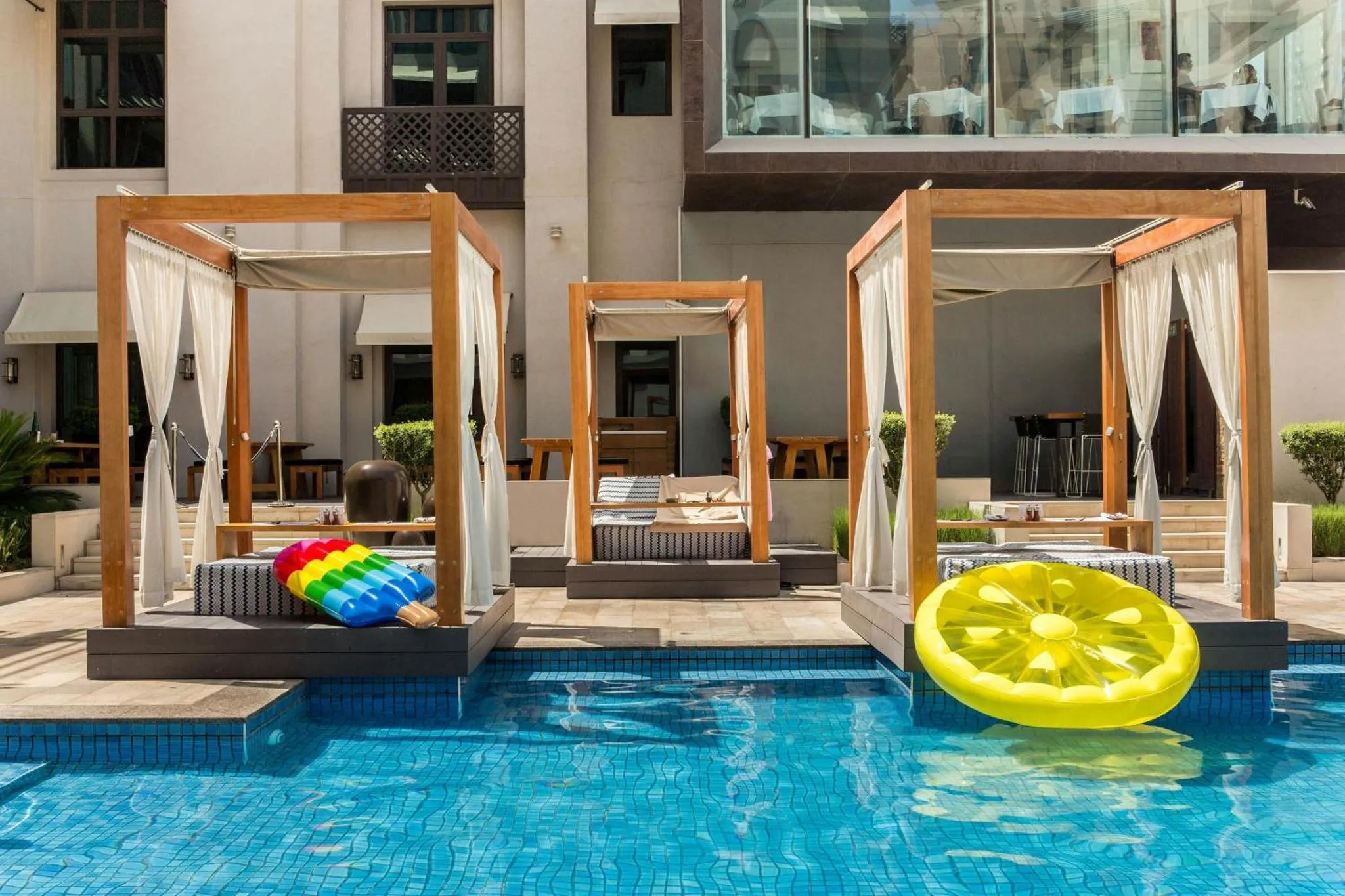 Espaces de détente avec des lits baléares au bord d'une piscine ensoleillée.