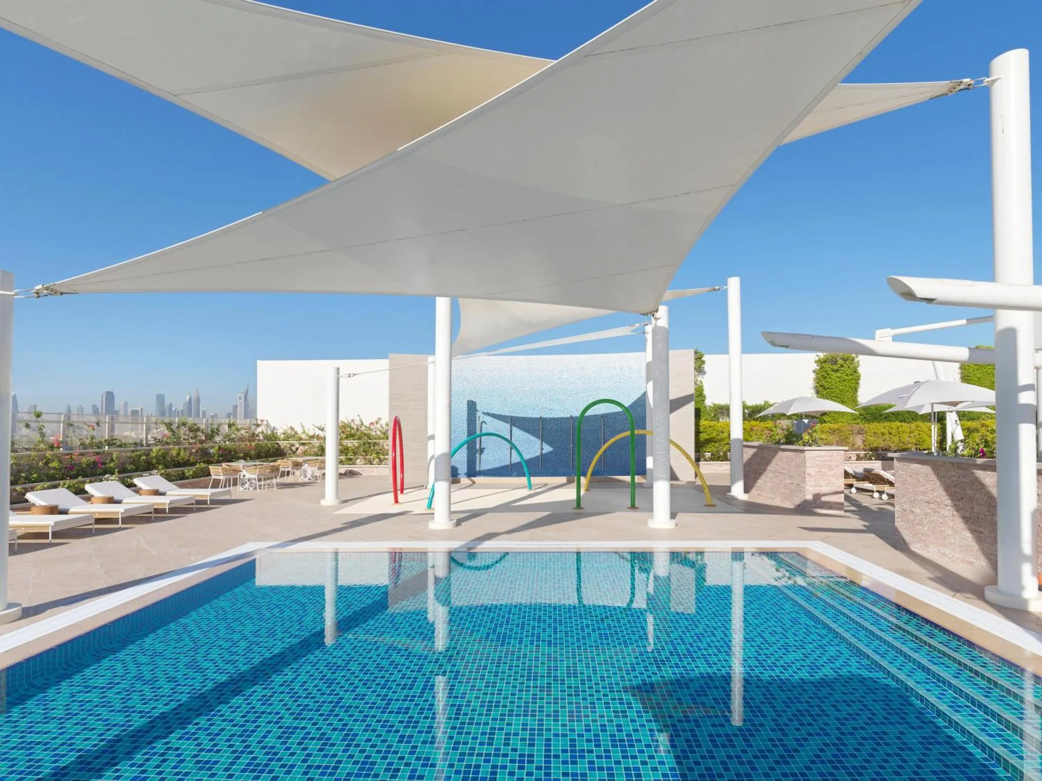 Terrasse ombragée avec piscine et mobilier de détente.