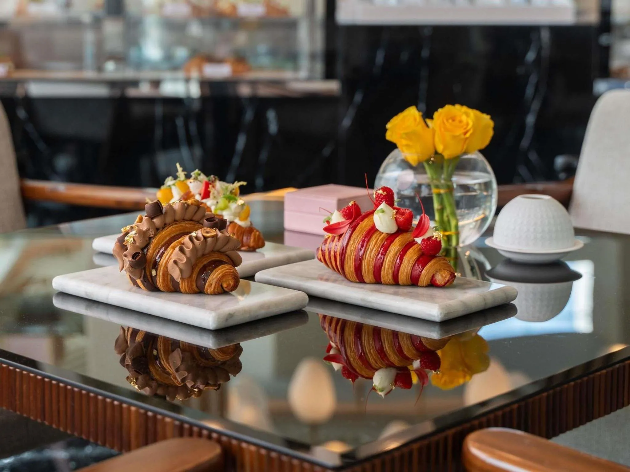 Des pâtisseries artistiquement présentées sur une table réfléchissante.