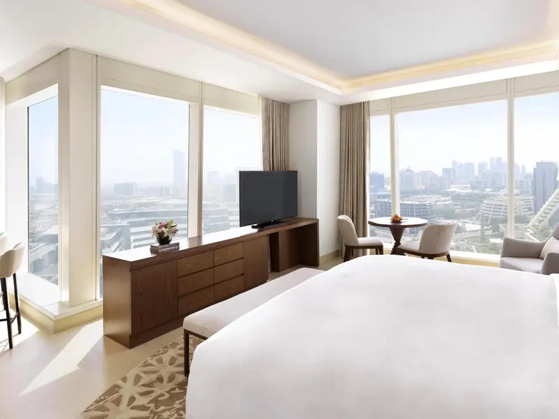 Chambre lumineuse avec un grand lit et une vue sur la ville.