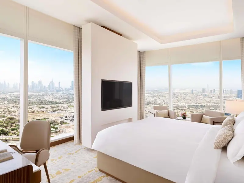 Chambre lumineuse avec un grand lit et une vue sur la ville.
