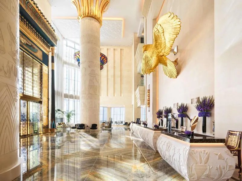 Vaste hall d'accueil avec comptoir de réception et décoration dorée.