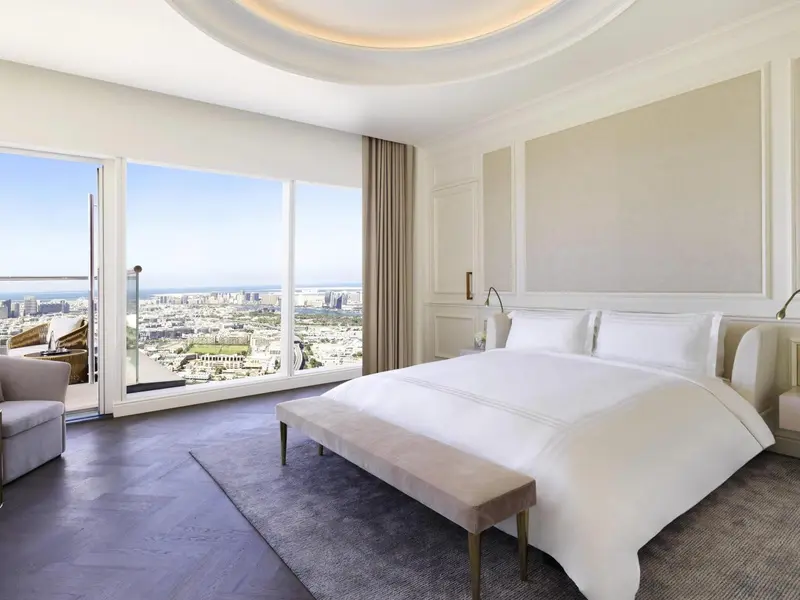 Chambre lumineuse avec un grand lit et une vue sur la ville.