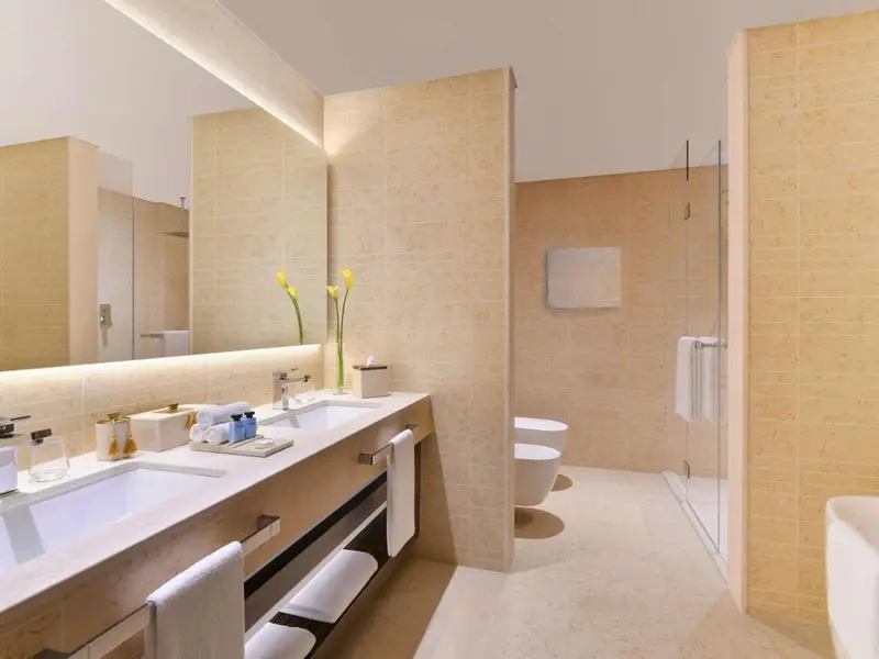 Une salle de bain lumineuse avec une douche vitrée et un double vasque.