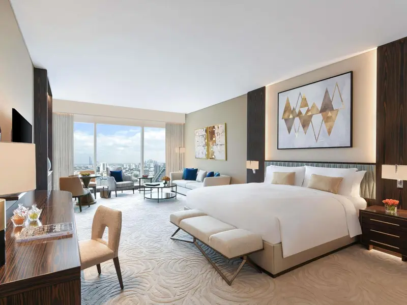 Une chambre lumineuse avec un grand lit et un espace salon.