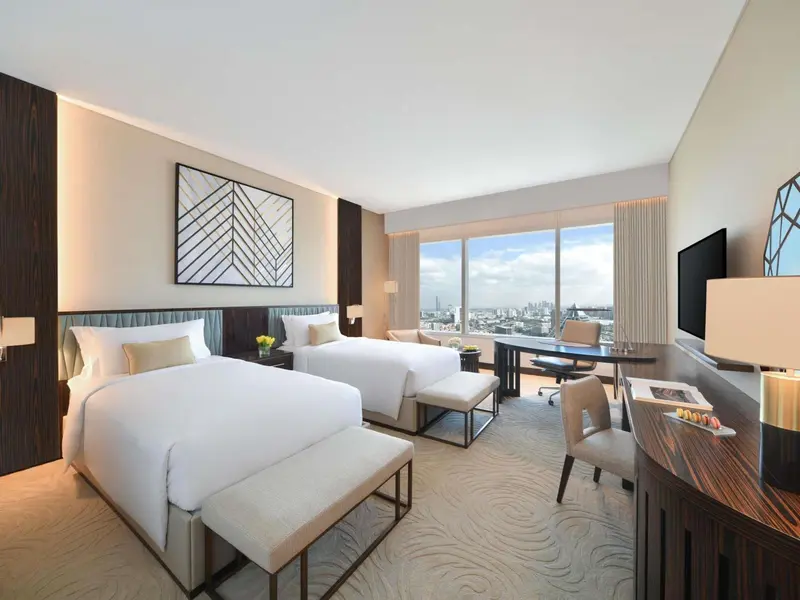 Chambre d'hôtel moderne avec deux lits et une vue sur la ville.