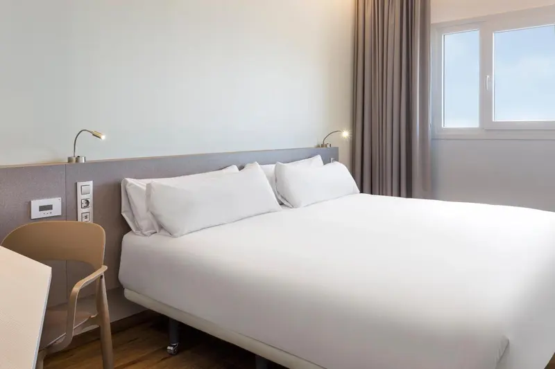 Une chambre d'hôtel moderne avec un grand lit blanc et des lampes de chevet.