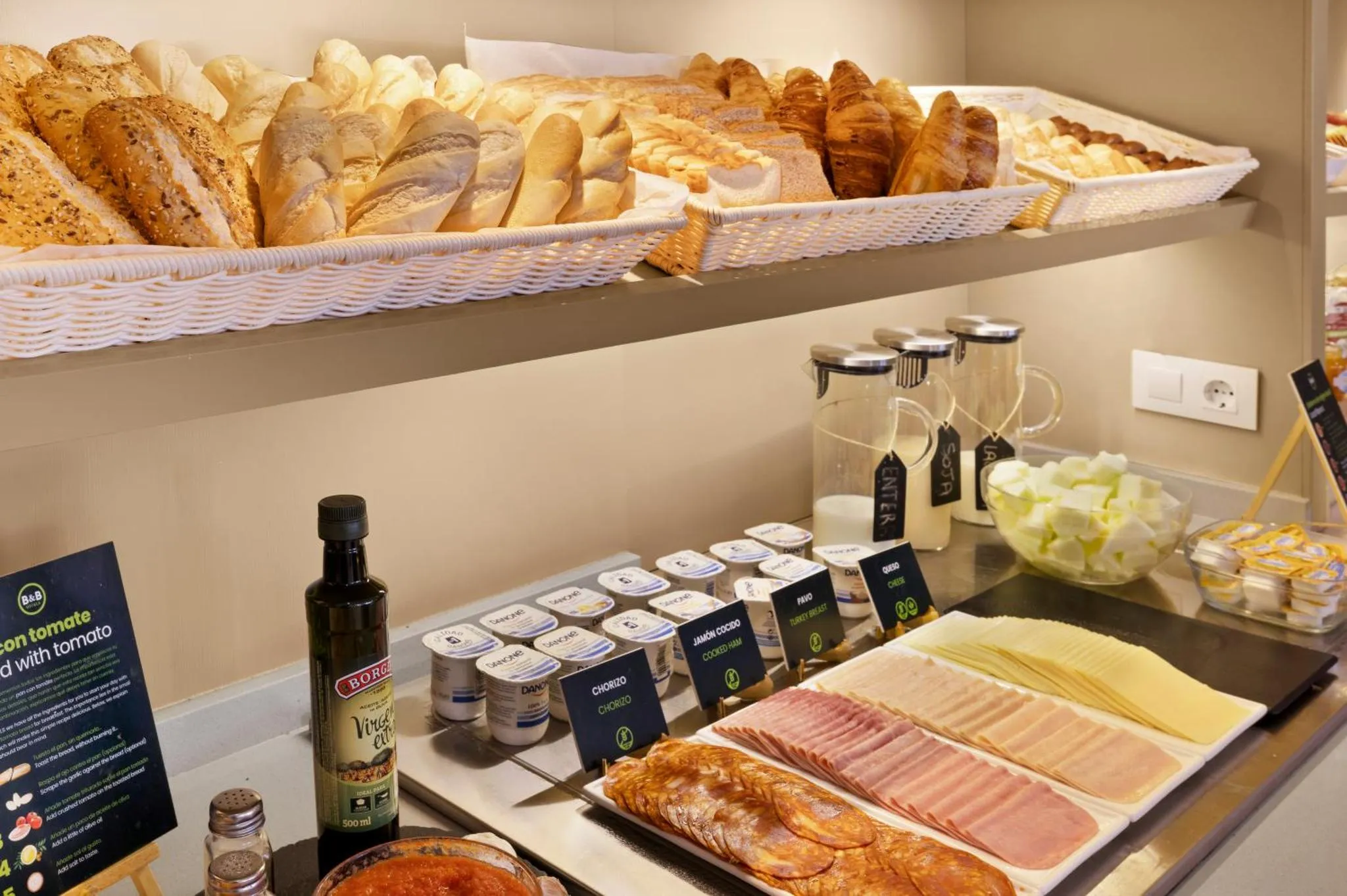 Un buffet propose une variété de pains, de viennoiseries, de charcuteries et de boissons.