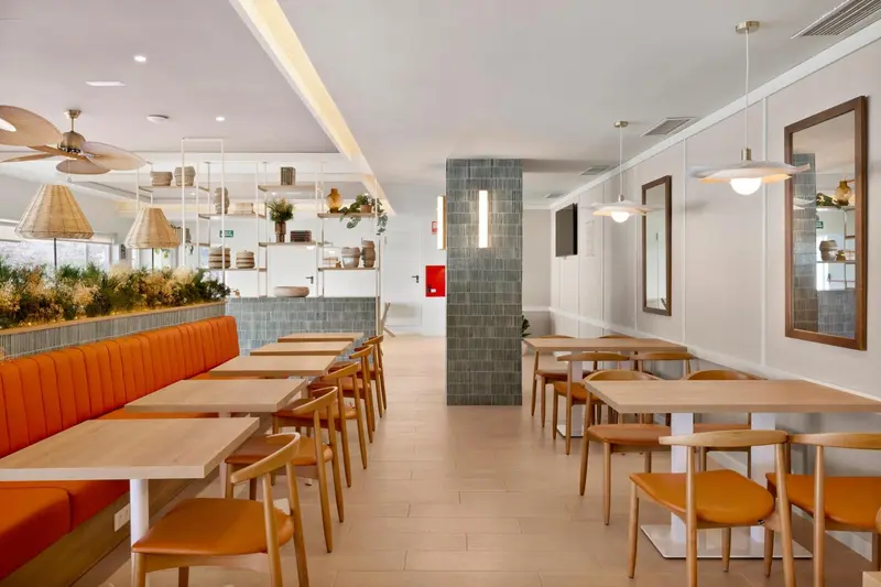 Une salle lumineuse avec des tables et des banquettes orange.