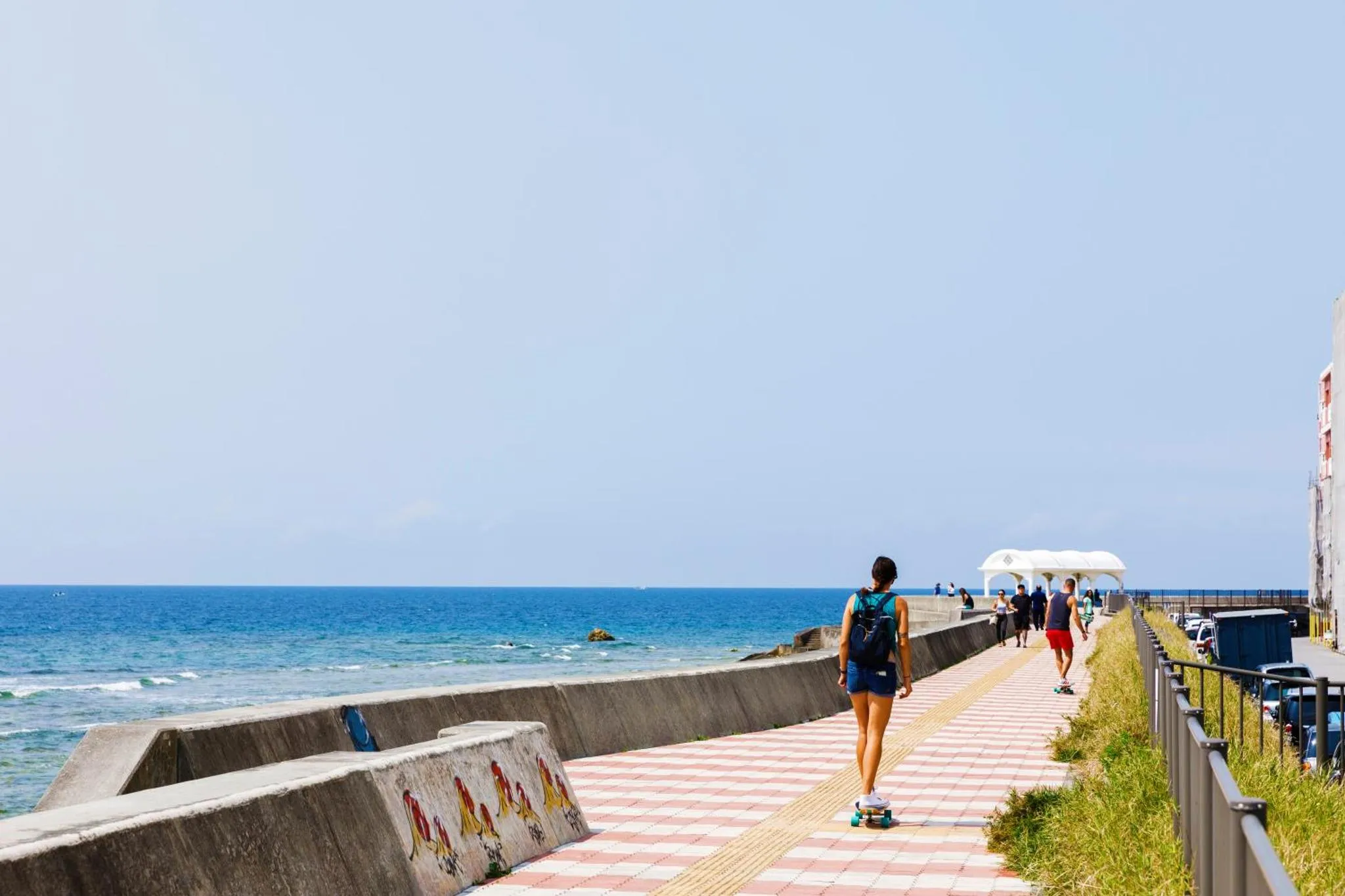 Une promenade en bord de mer avec des personnes et une vue sur l'océan.