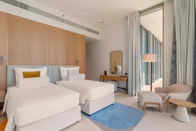 Une chambre lumineuse avec deux lits simples et un coin salon.