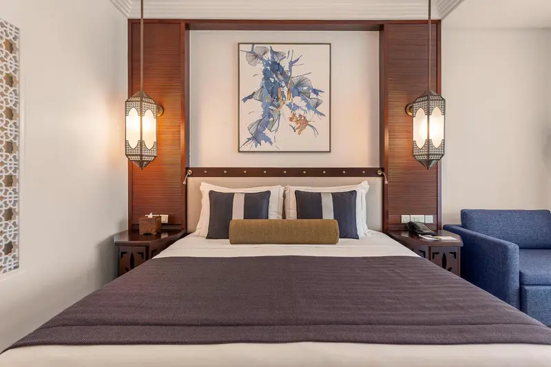Un lit double est dispose dans une chambre decorée avec des tons neutres et des accents de bleu.