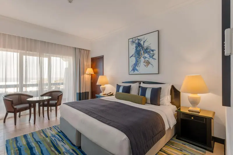Chambre lumineuse avec un grand lit et un coin salon.