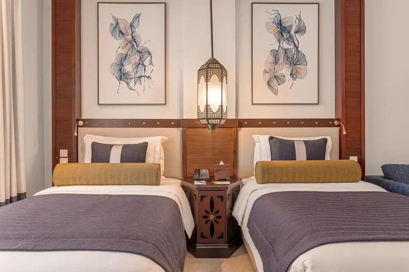 Deux lits simples avec chevet et décoration murale dans une chambre.