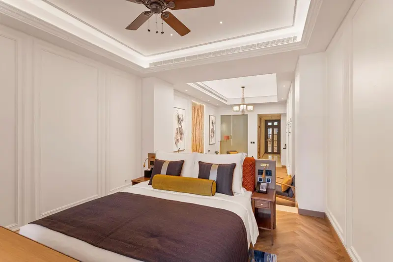 Une chambre lumineuse avec un grand lit et un parquet clair.