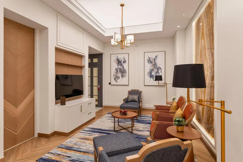 Un salon lumineux avec des fauteuils et un éclairage décoratif.