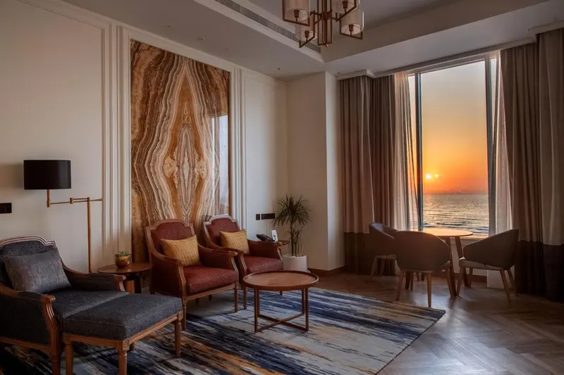 Un espace de détente intérieur avec des fauteuils et une vue sur la mer au coucher du soleil.