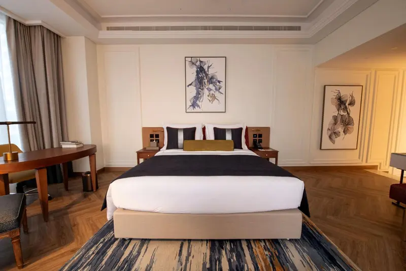 Une chambre spacieuse avec un grand lit et des œuvres d'art murales.