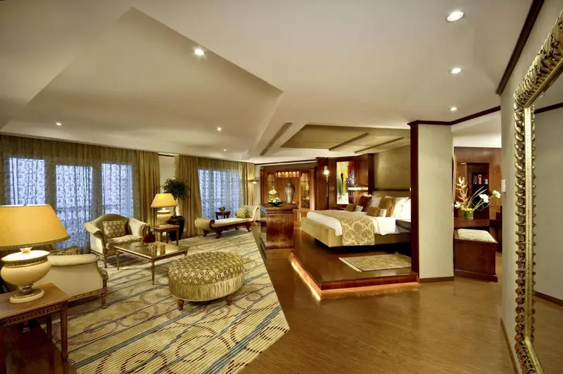 Une chambre spacieuse avec un coin salon et un lit surélevé.