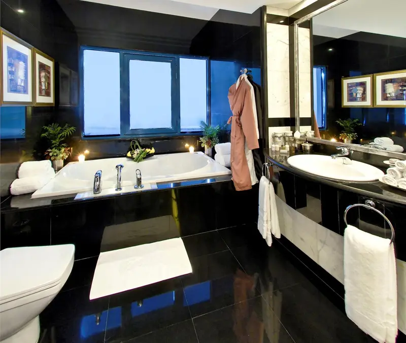 Une salle de bain luxueuse avec baignoire et lavabo en marbre noir.