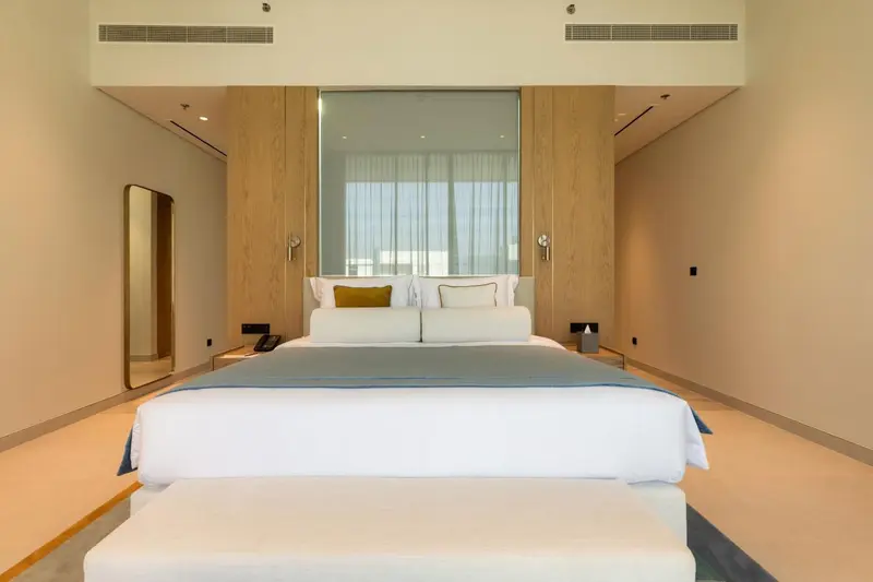 Une chambre lumineuse avec un grand lit recouvert d'une courtepointe bleue et de coussins.