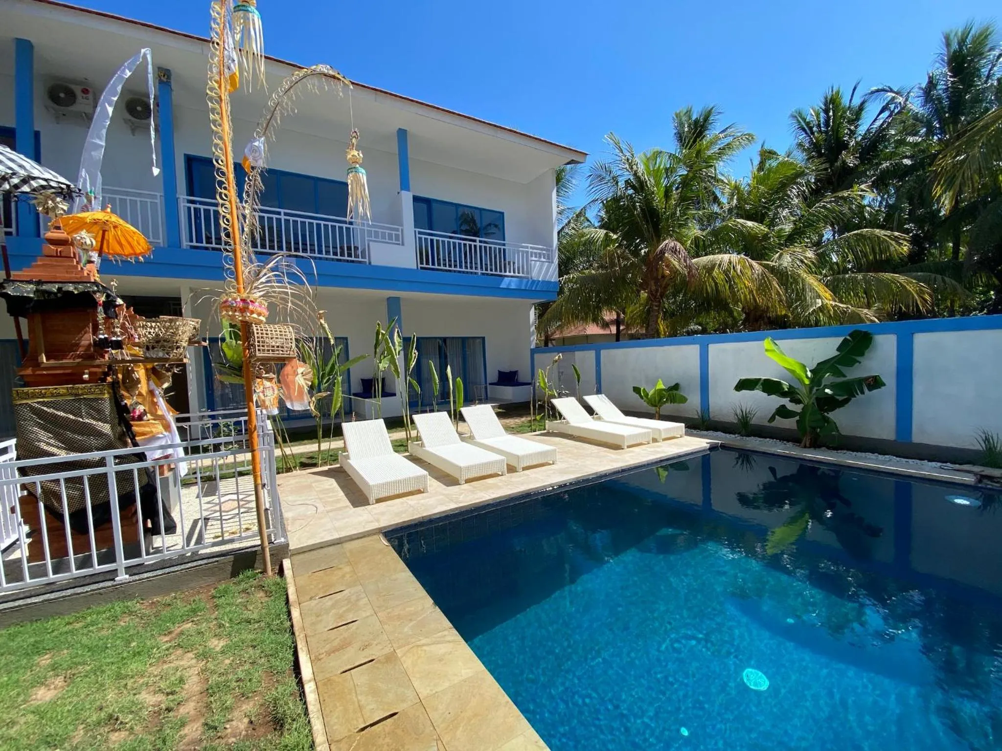 Transats blancs disposés au bord d'une piscine turquoise dans un jardin tropical.