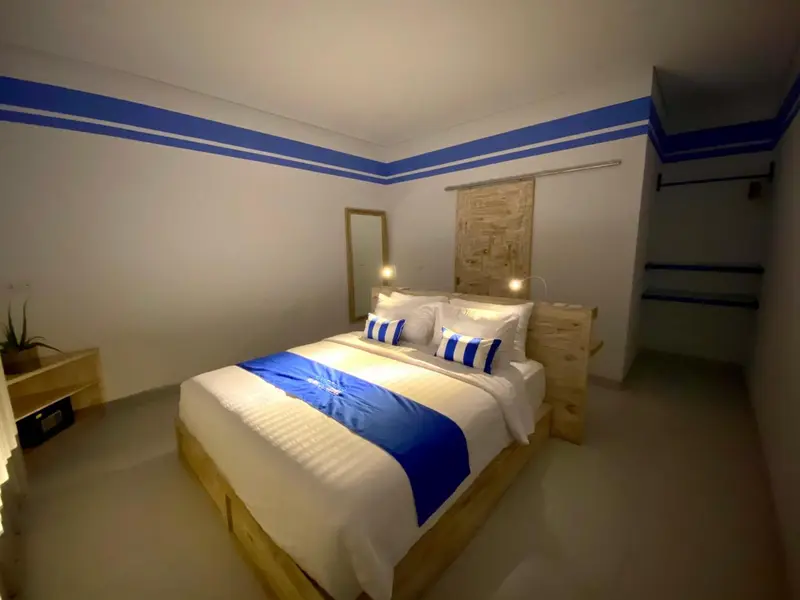 Une chambre lumineuse avec un grand lit recouvert d'une courtepointe bleue.