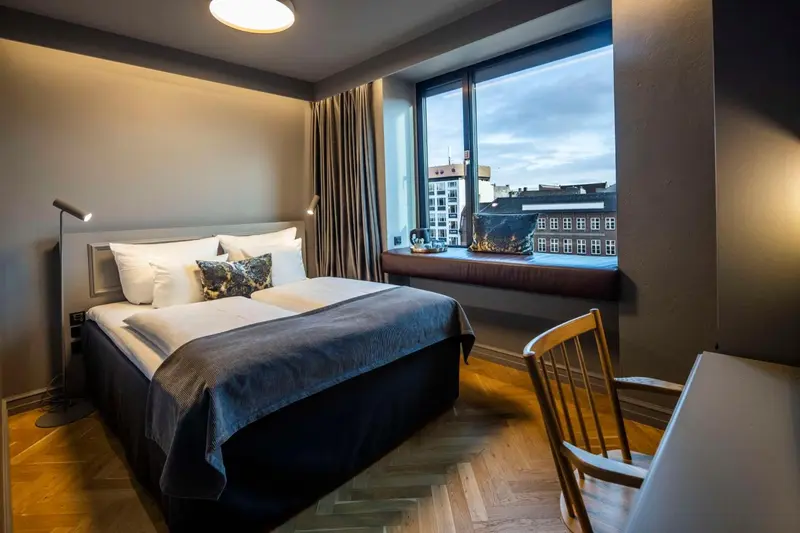 Une chambre avec un grand lit et une fenêtre donnant sur une ville.