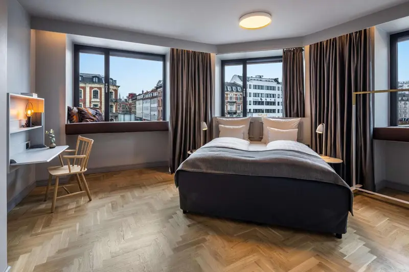 Une chambre lumineuse avec un grand lit et un bureau près de la fenêtre.