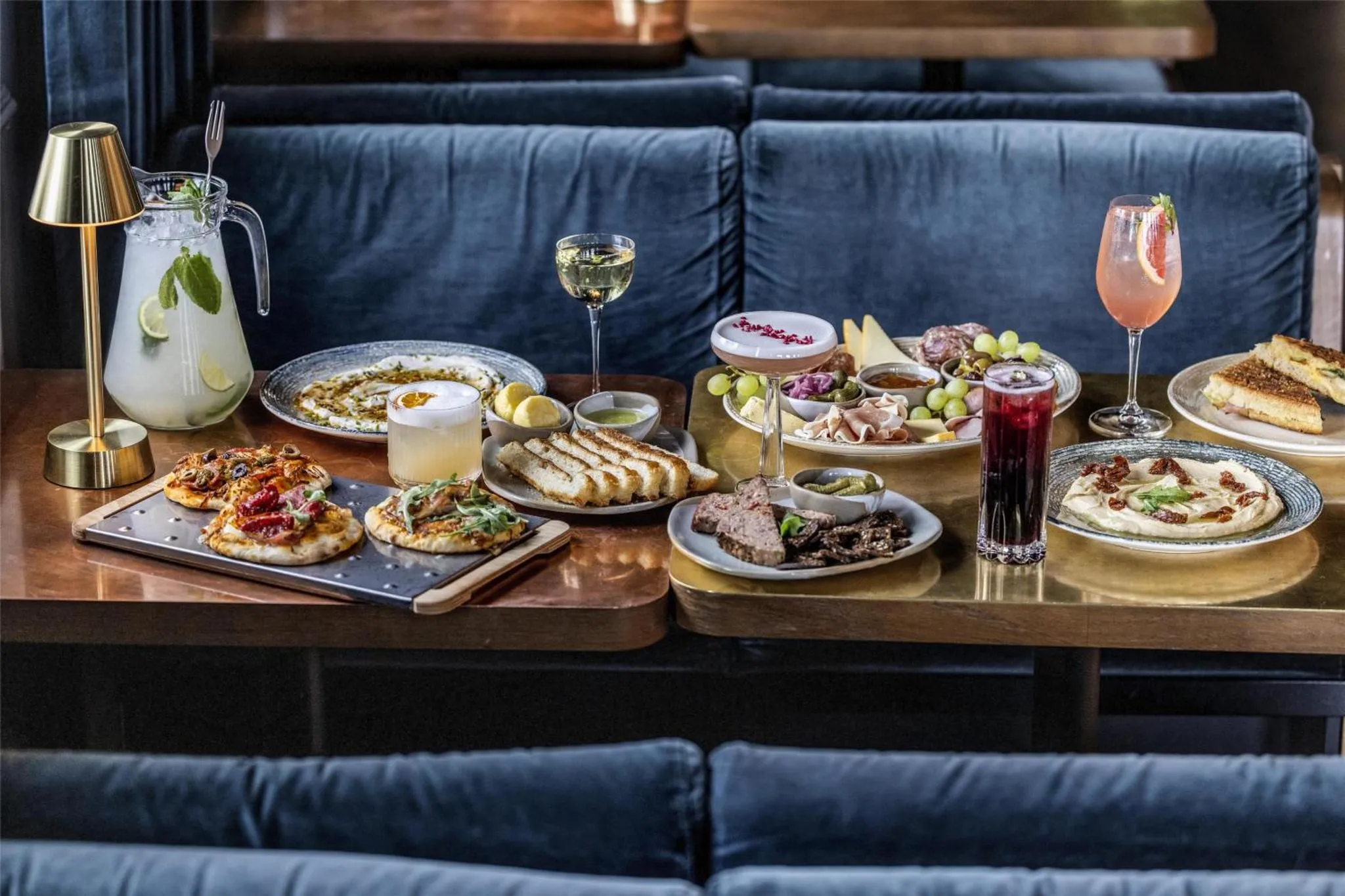 Une table garnie de plats et de boissons colorées est mise en scène dans un intérieur soigné.
